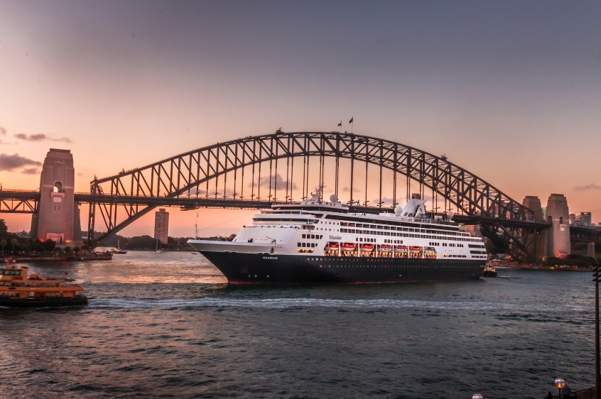 a huge cruise ship on sail near Sydney Harbour Bridge