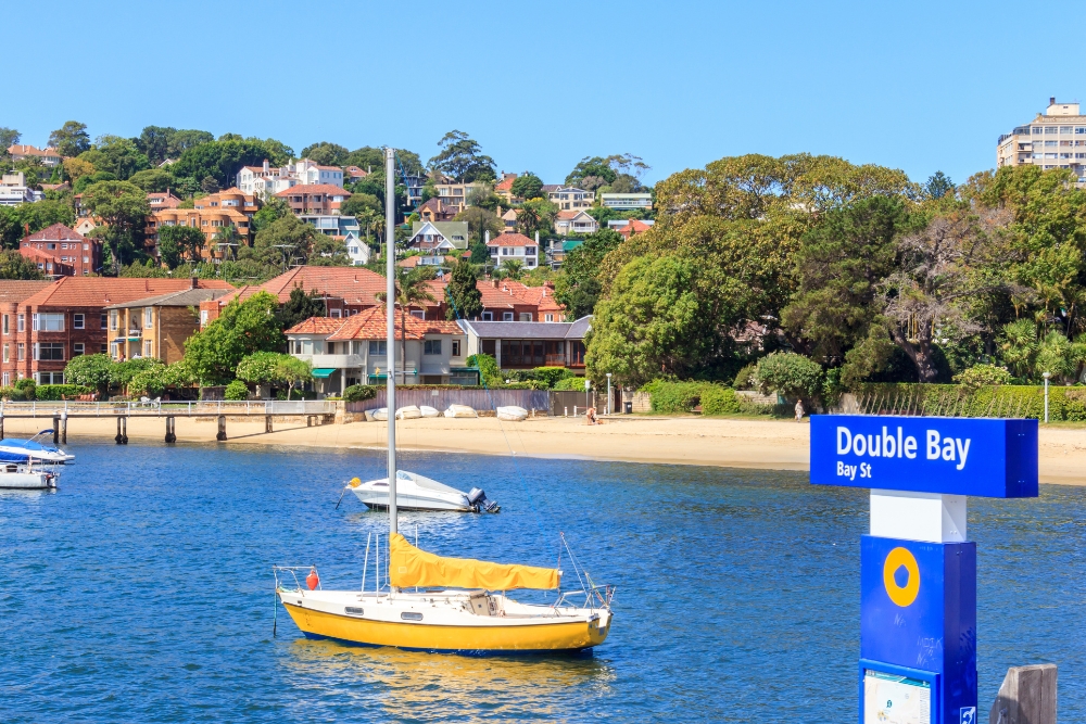A yellow sailboat anchored in the blue waters of Double Bay, Sydney